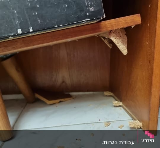 שולחן עץ שבור עם שבבי עץ על הרצפה